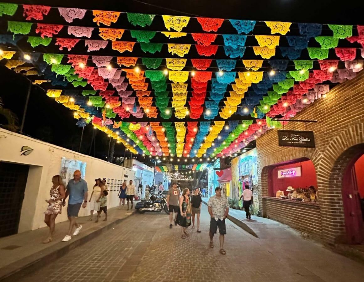 people walking under brightly colored strands at the san josé del cabo festival