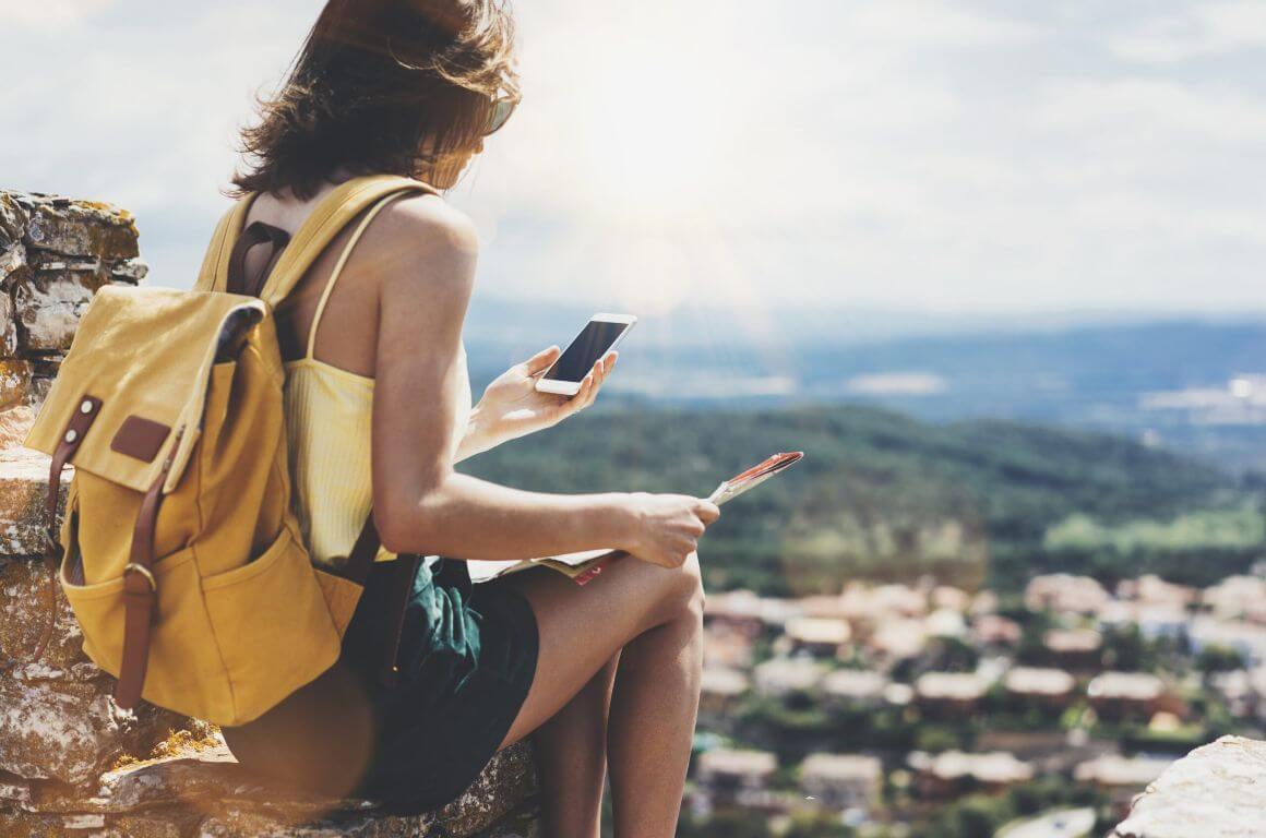 young female wearing bright bag pack overlooking city