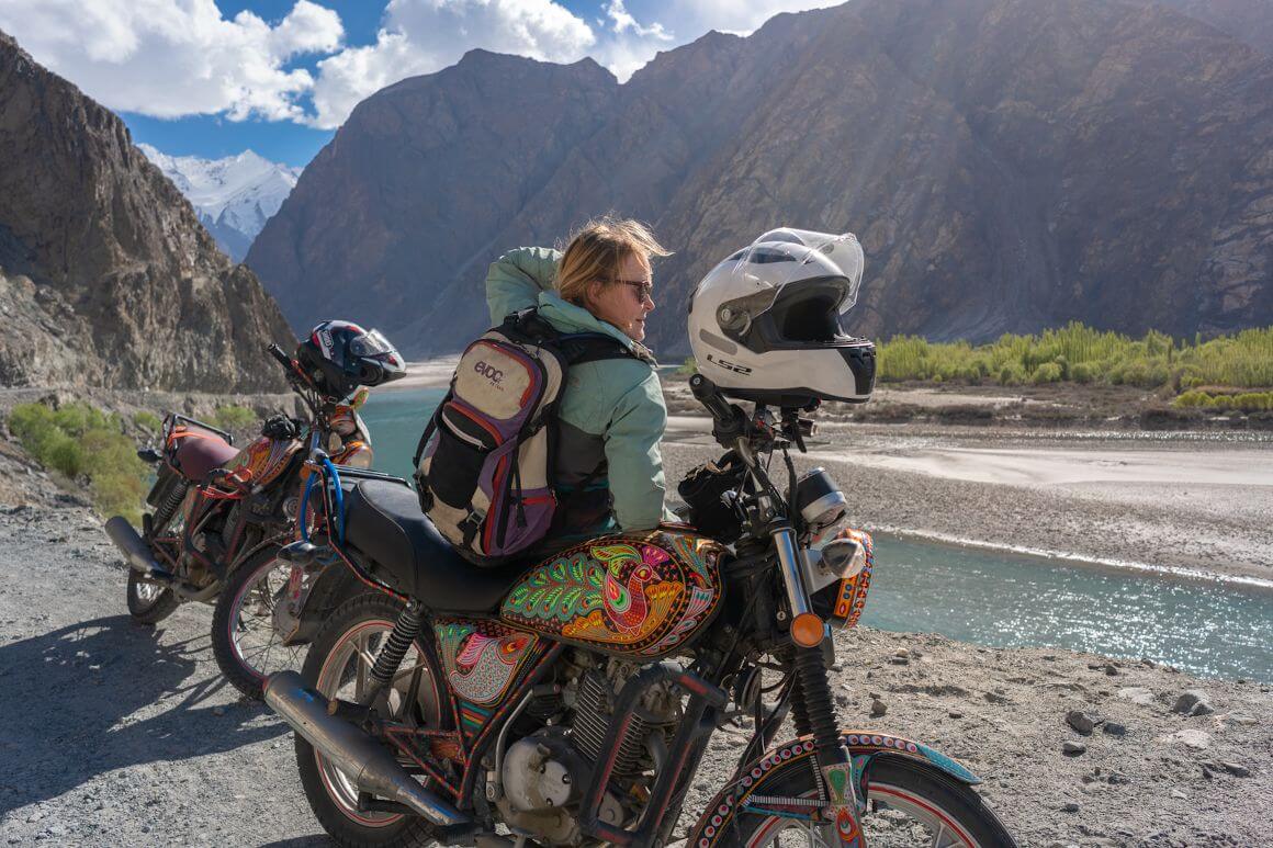 a girl leaning against a colored motorbike on a lost with purpose pakistan motorbike tour