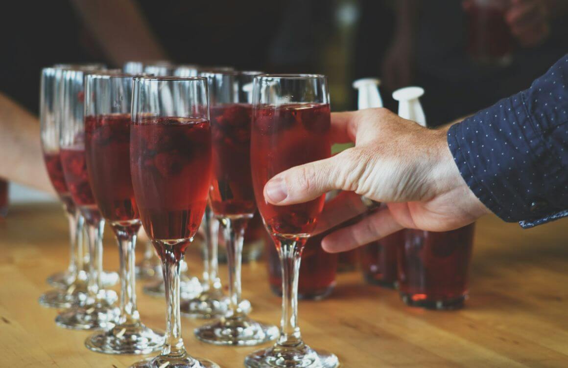 man grabbing a wine glass on table