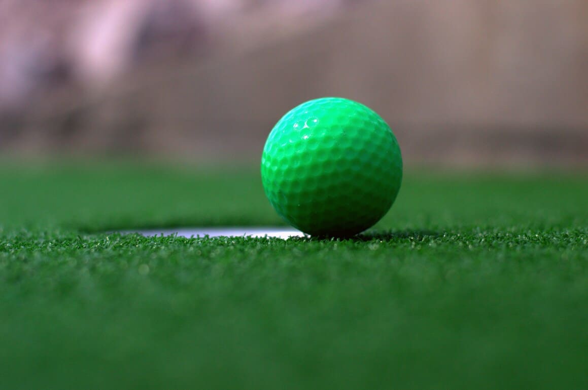 A green golf ball on a mini golf green