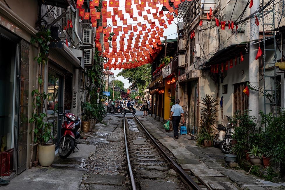 Train street in Hanoi with Vietnamese flags hanging down
