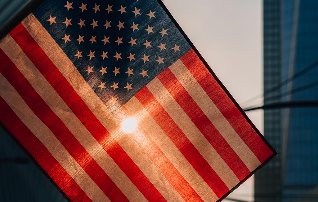 A USA flag flying with sun coming through