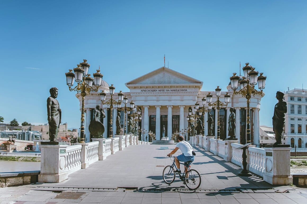 Man on a bike in Skopje, Macedonia with ancient architecture and bridge