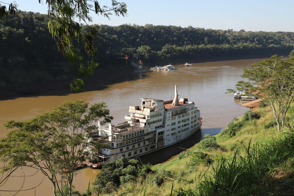 abandoned ship docked on a wide, brown river
