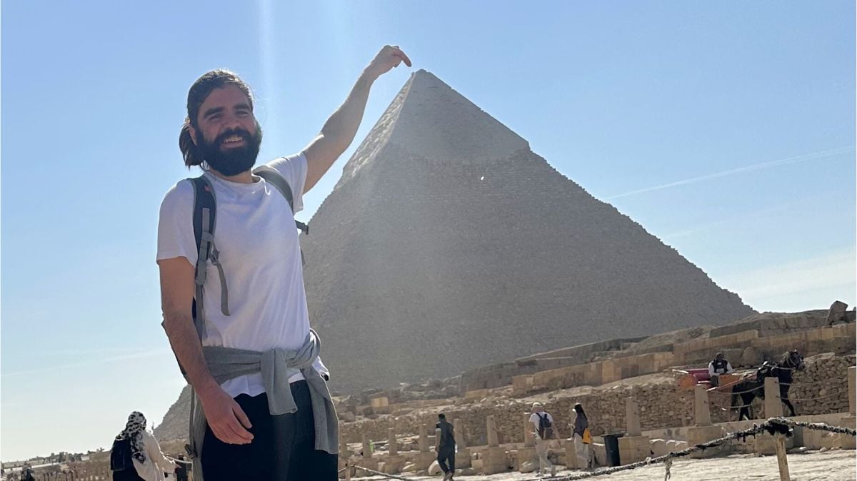 a traveller pretending to touch the top of the great pyramids of giza in cairo, egypt