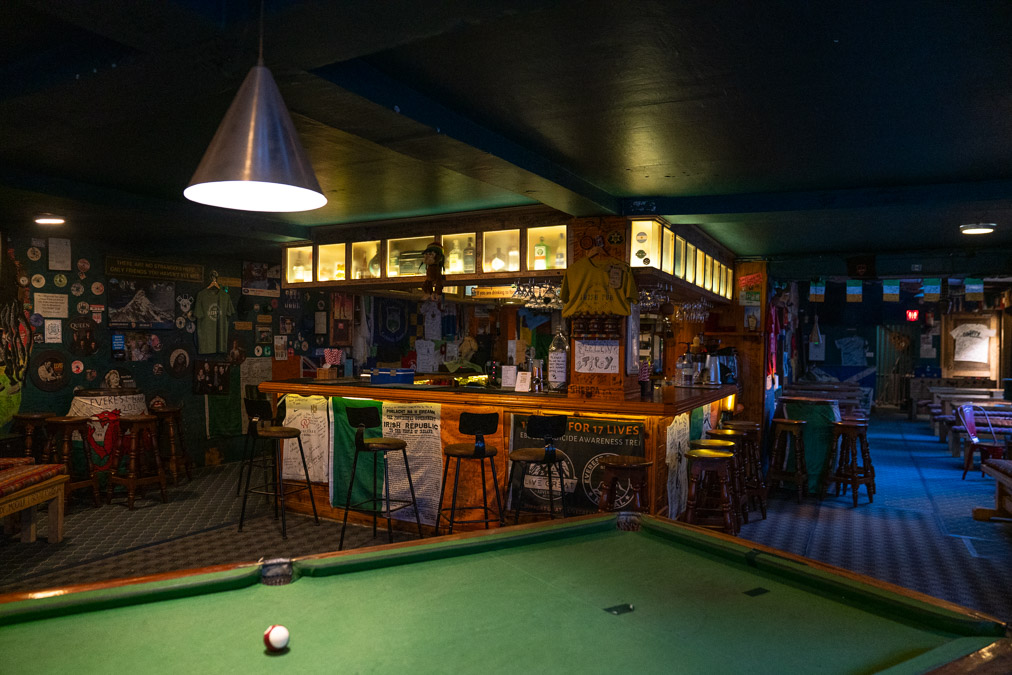 an irish pub in namche bazaar nepal with a green pool table and a wooden central bar with the irish flag hung on it