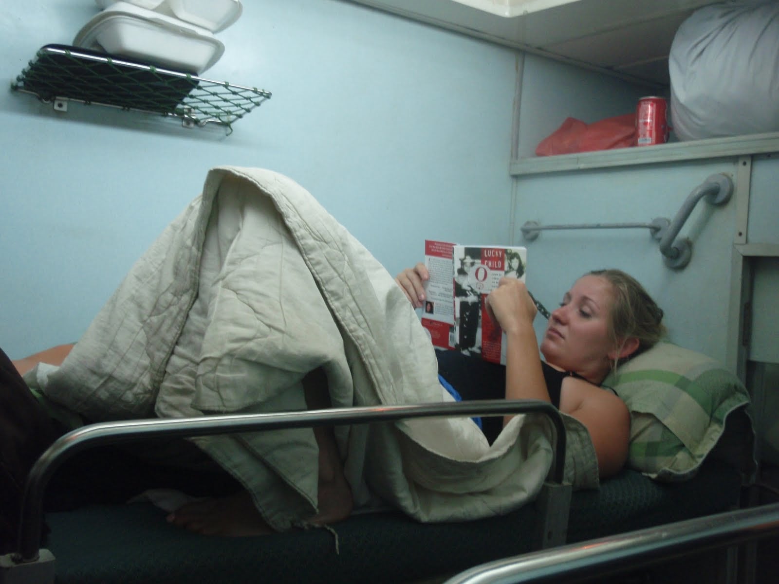 Woman reading a book on the top bunk of a sleeper cabin on the train from Ho Chi Minh City to Hanoi