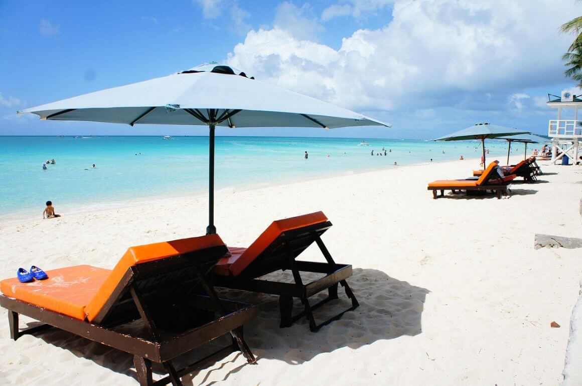 sunny weather on a white sand beach with lounge chairs