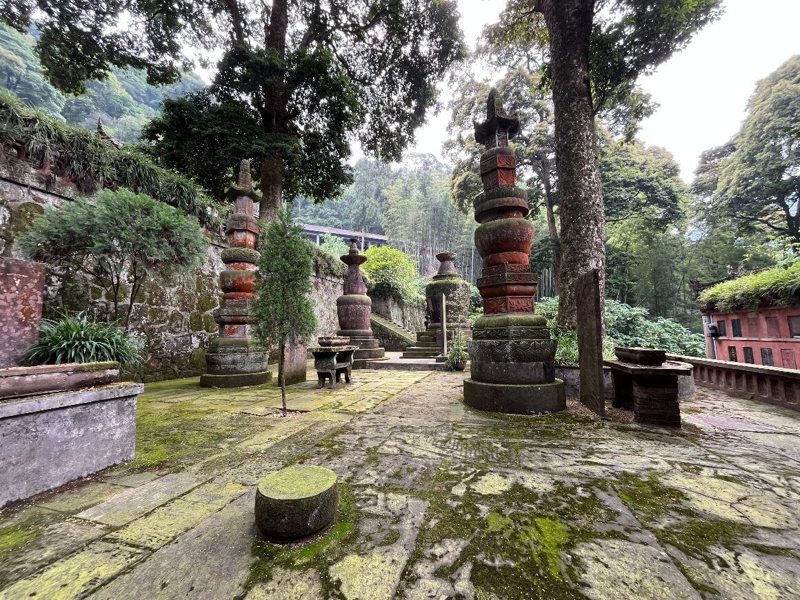 stone pagoda monuments with moss ground and trees everywhere