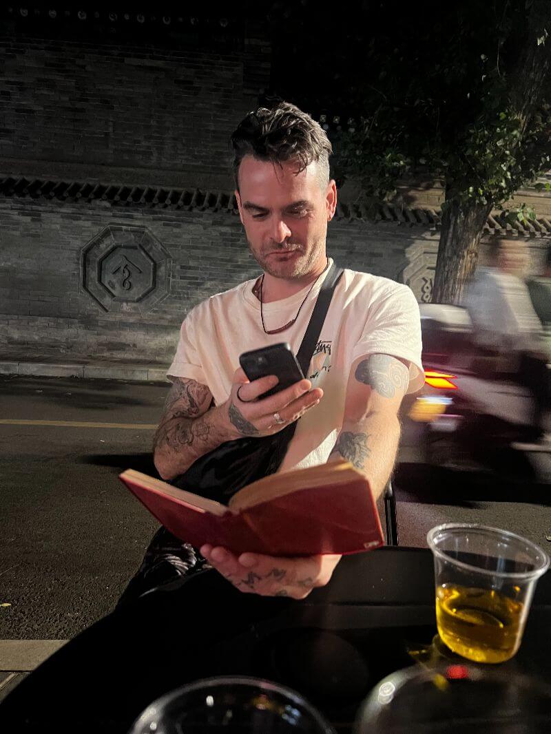 man holding phone with esim, taking photo of book