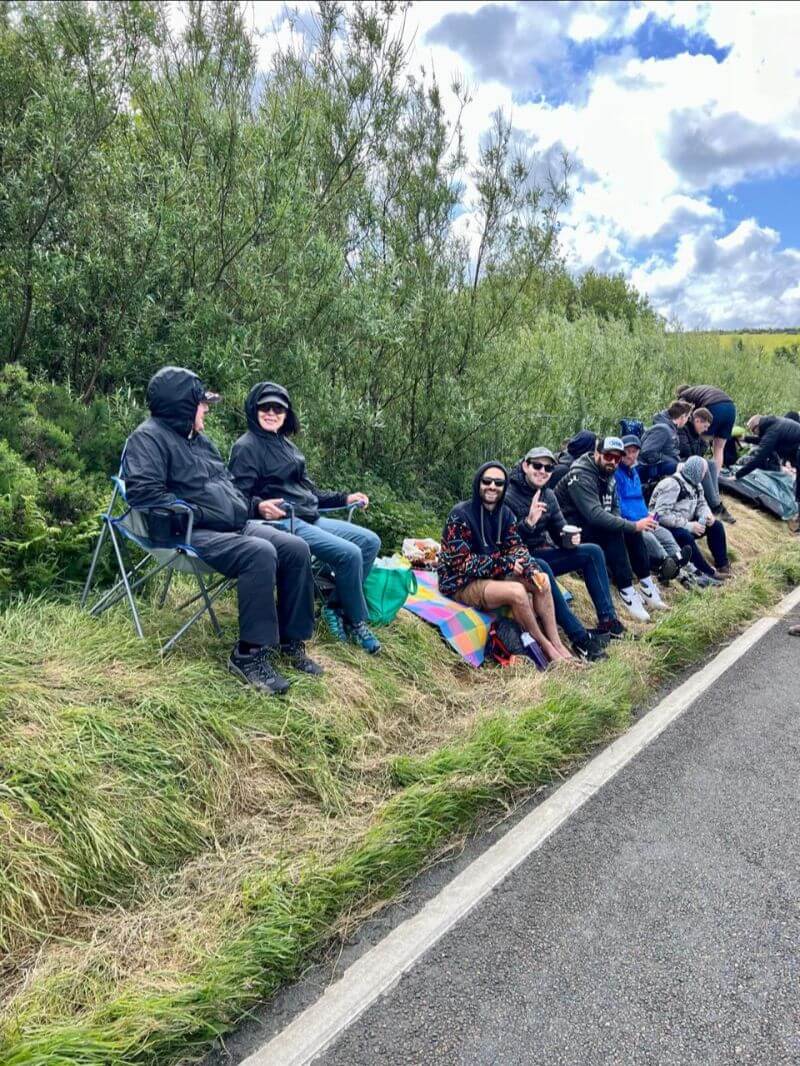 group of people sitting on the edge of a grassy road