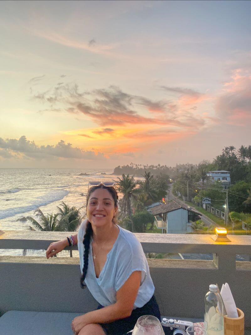 female traveler sitting on a roof cafe with sunset view at the background