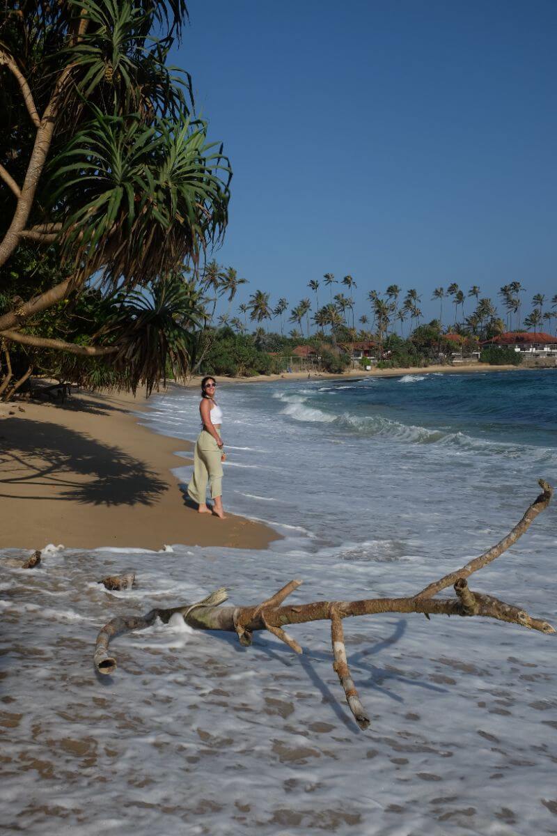 woman walking by seashore with tree log by the sea