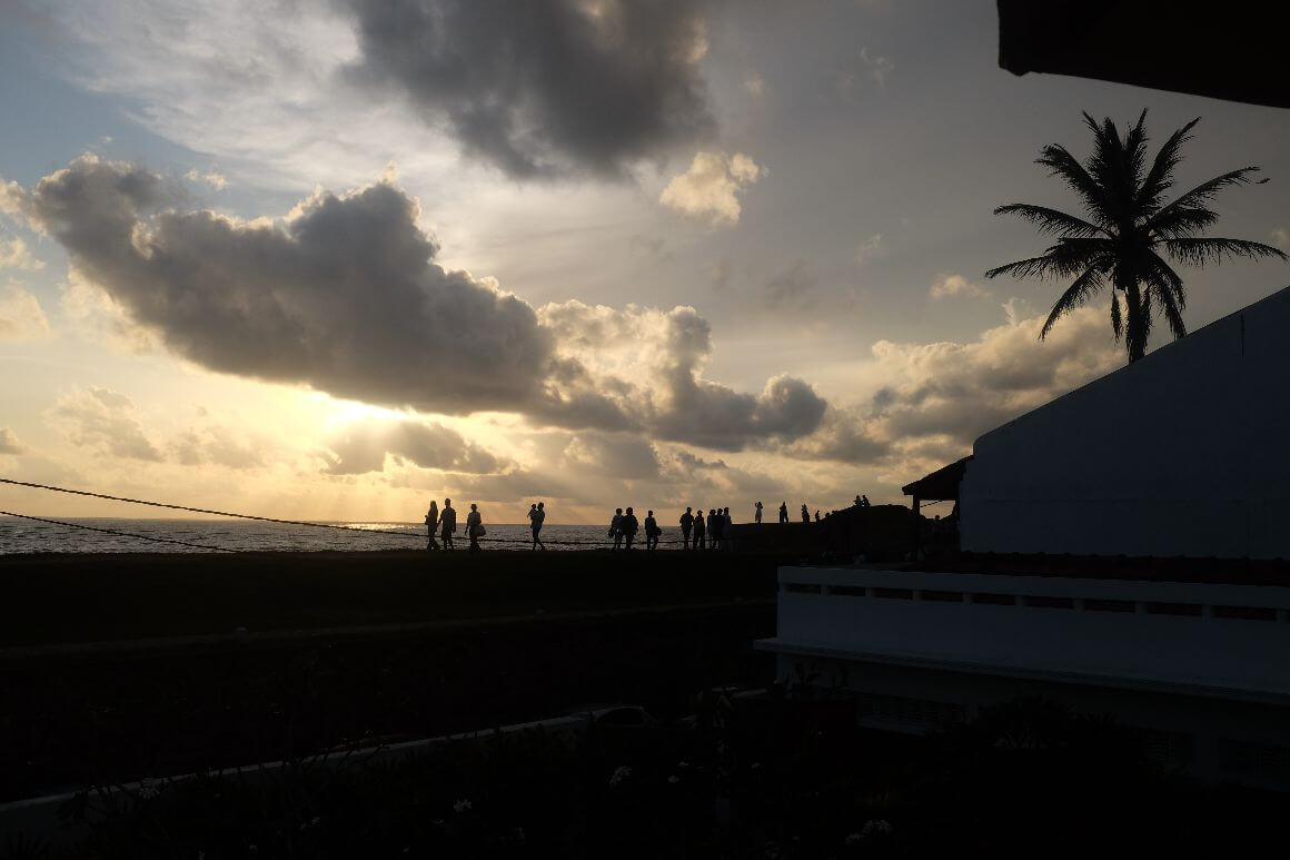 crowd of people looking at sunset on top of seawall