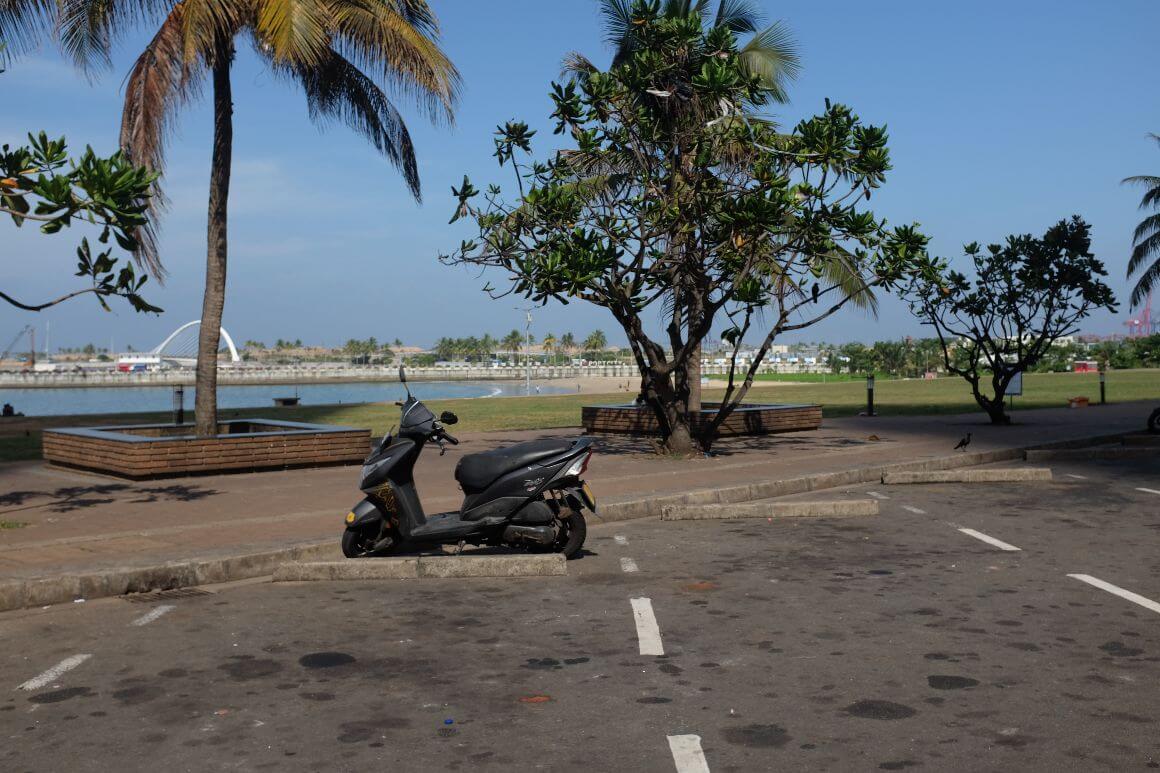 single scooter on a parking lot, near a scenic park and river