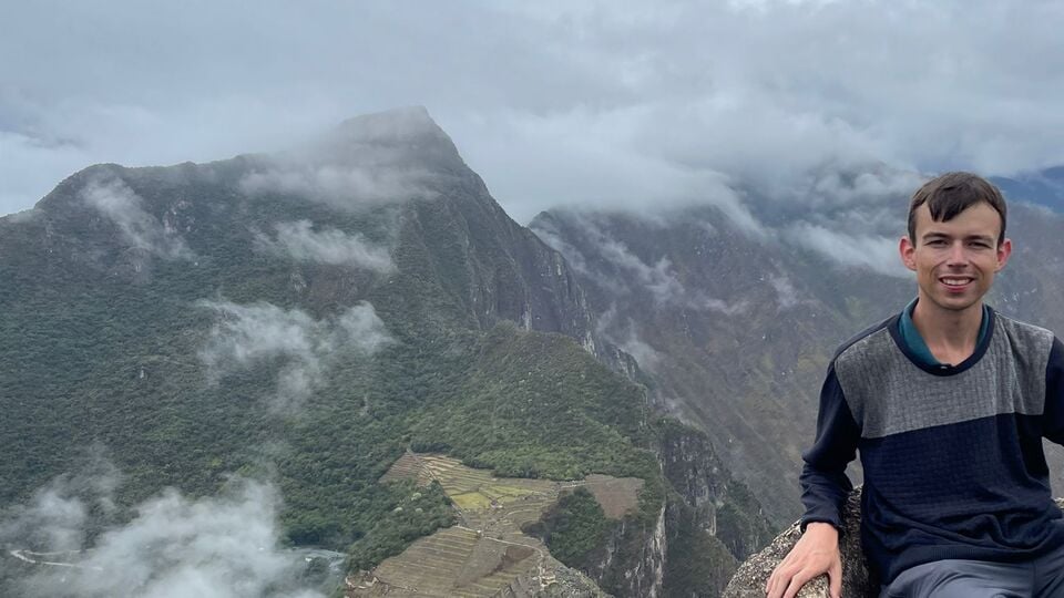 Alex sat on top of Huayna Picchu Mountain, overlooking Machu Picchu.