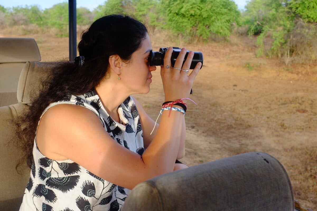 A woman with a pair of binoculars Udawalawe National Park in Sri Lanka on Safari sitting in a jeep