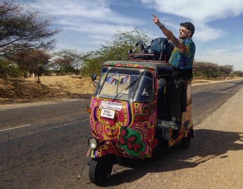 Will hanging out of the side of a Rickshaw and pointing in India