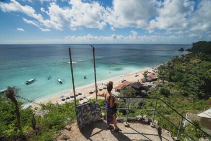 A person standing looking down over uluwatu beach viewpoint in Bali