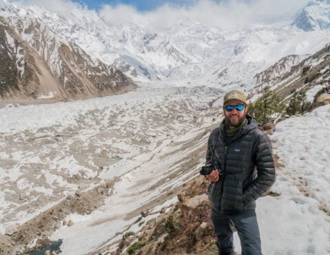A person in a down jacket with a camera in the mountains