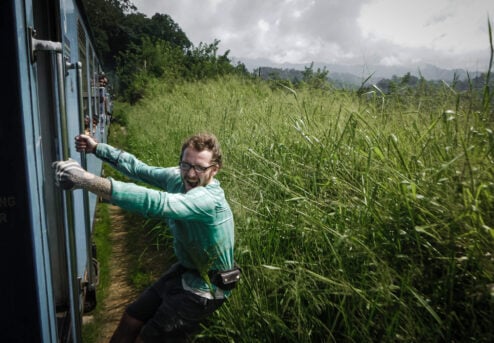 adventurous traveller hanging from a train in sri lanka