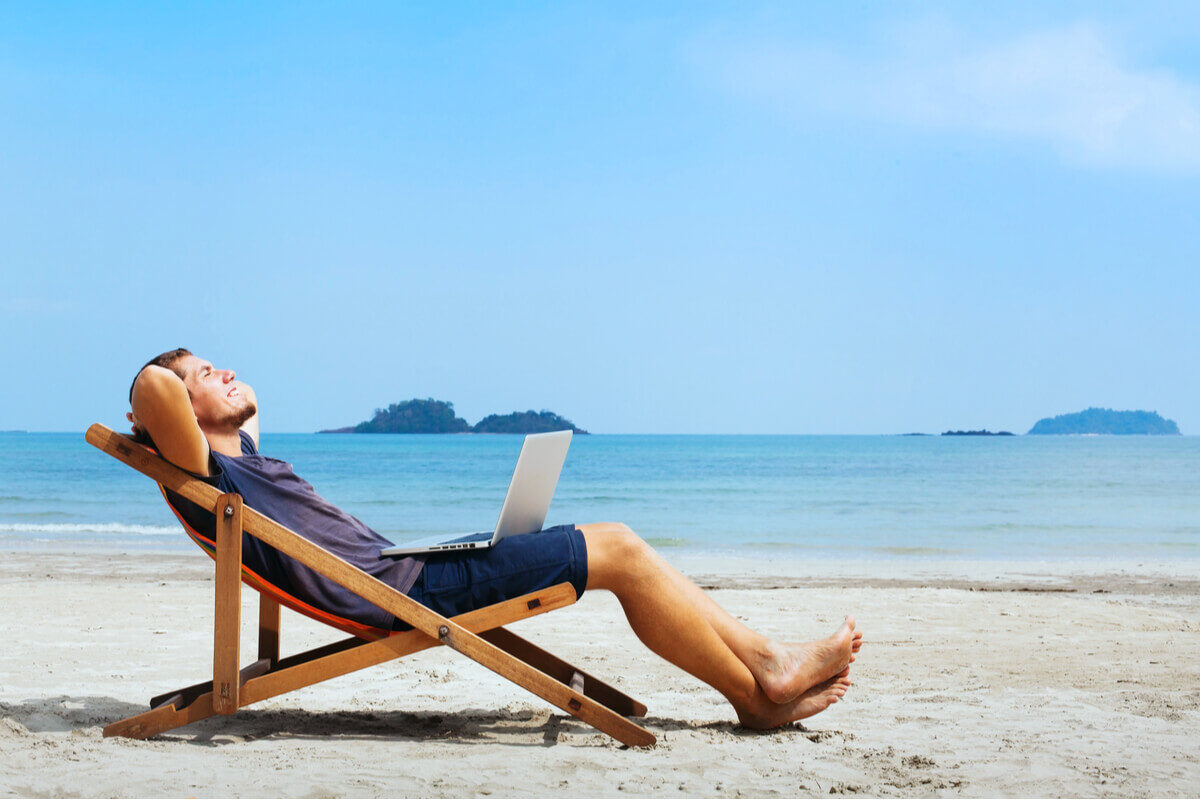 digital nomad chilling on the beach with a laptop