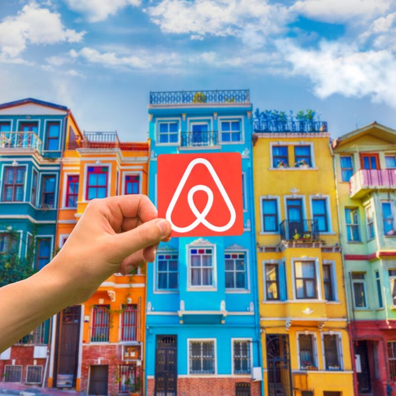 airbnb logo in front of colourful houses