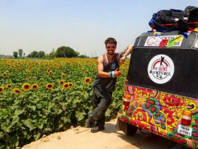 will hatton standing next to his psychedelic tuk tuk in india