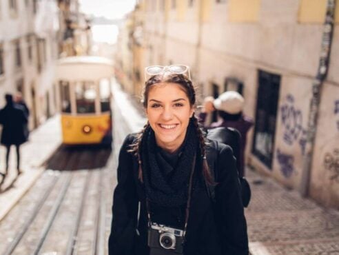 woman with a camera smiling while traveling in lisbon