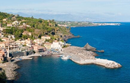 The small sea village of Santa Maria al Scala in Sicily with lush trees and buildings