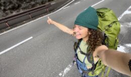 Solo female hitchhiker takes selfie as she waits for a ride in Japan.