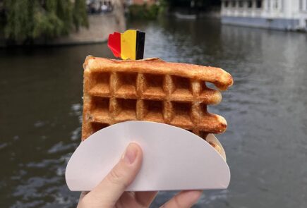 Holding up a waffle near a canal in Belgium