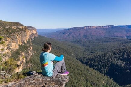 A person sitting on a cliff looking out in the Blue Mountains in New South Wales, Australia