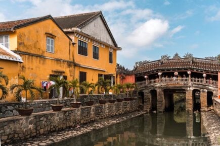 The Japanese bridge in Hoi An and typical yellow painted houses near by in Vietnam