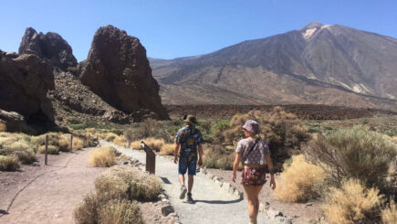 Two people walking towards el teide moutain in tenerife on a sunny day