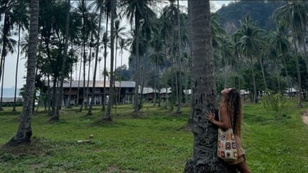 a girl hugging a palm tree in a field full of palm trees in Thailand