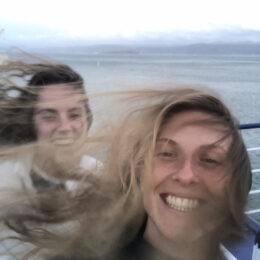 two friends on a windy boat ride with hair blowing everywhere