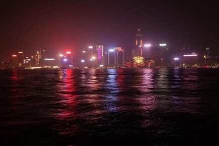 The skyline of Hong Kong, China lit up at night across the water.