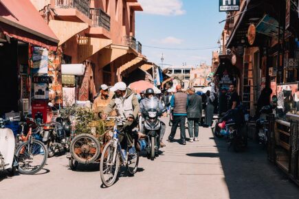 A busy street with people, motorbikes and shops in the medina in Marrakech, Morocco.