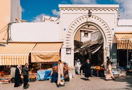 People walking around the medina gateway in Tangier, Morocco.