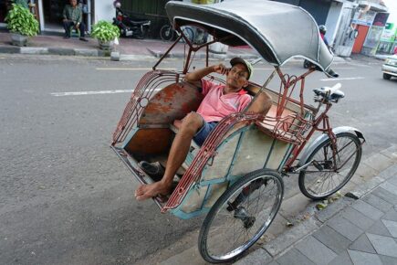 A man taking a nap in a rickshaw in Yogyakarta, Indonesia.