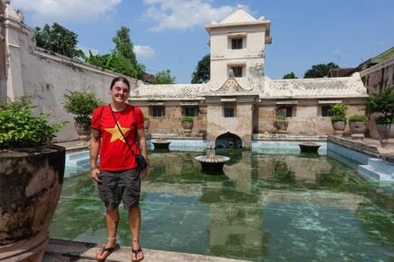 A person standing in front of the main pool of the water temple in Yogyakarta, Indonesia.