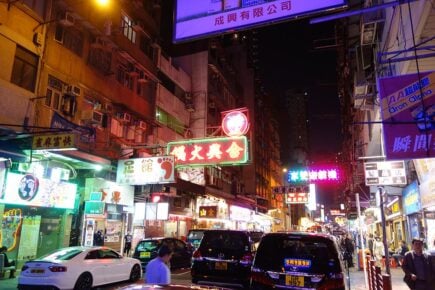 A busy street lit up at night by neon signs in Hong Kong.