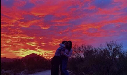 Friends embrace eachother in a hug as a colorful sunset fills the sky of Tucson Arizona. United States of America.