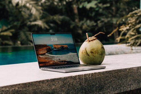 A laptop and a coconut next to the pool. Digital nomad.