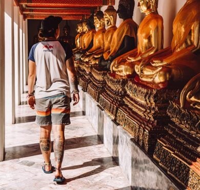 Nic walking past several gold buddhas at a temple in Bangkok, Thailand