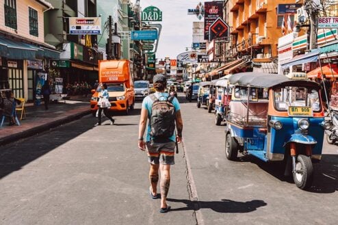 Nic walking down Khao San Road in Bangkok with a tuk tuk next to them