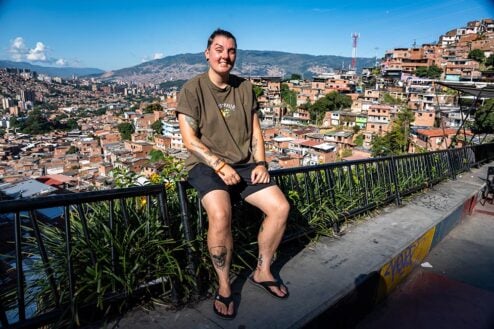 Nic sitting on a railing overlooking the area of Comuna 13 in Medellin, Colombia