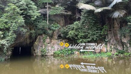 A lake leading to a cave surrounded by greenery in Ipoh, Malaysia